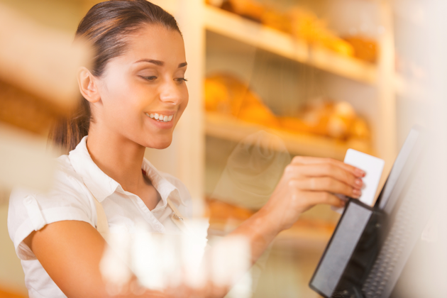 Woman accepting credit card payment at point of sale terminal